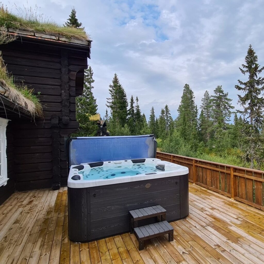 jacuzzi w ogrodzie inspiracje - jacuzzi na drewnianym tarasie z widokiem